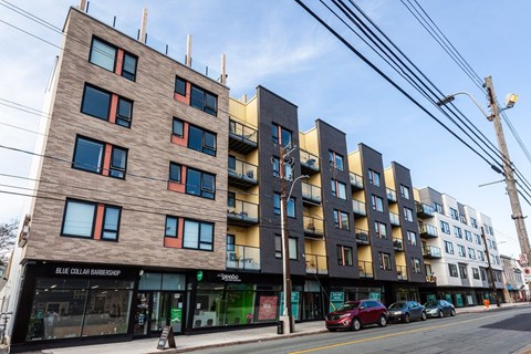 A street view of a multi-story building with a barbershop on the ground floor.