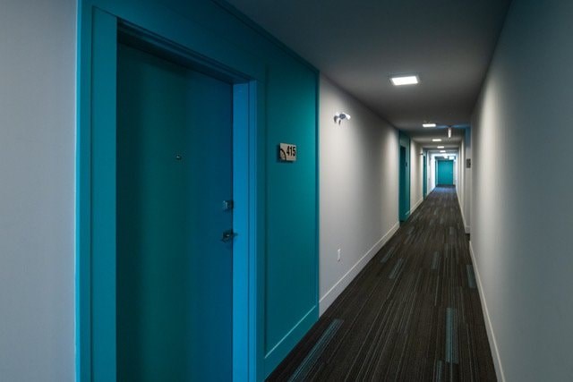 A long hallway with blue doors and wood flooring.