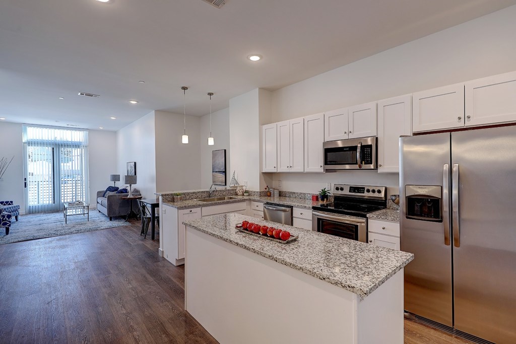 A modern kitchen with stainless steel appliances and a marble countertop.