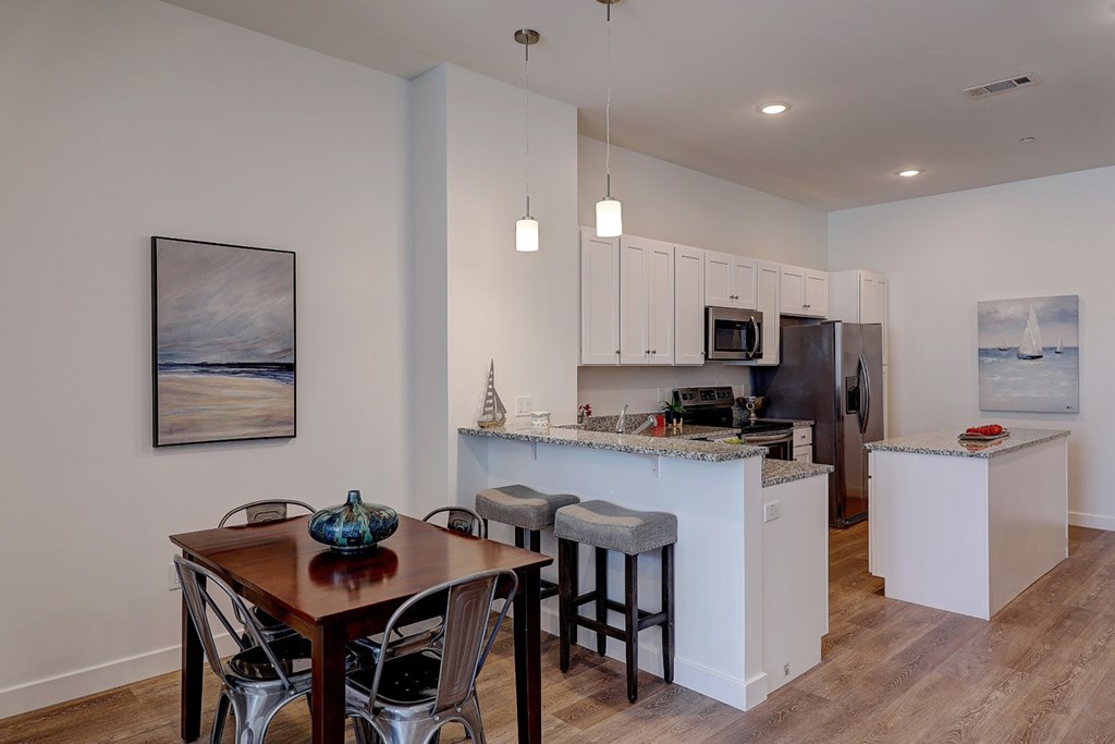 A kitchen with a table and chairs in front of it.