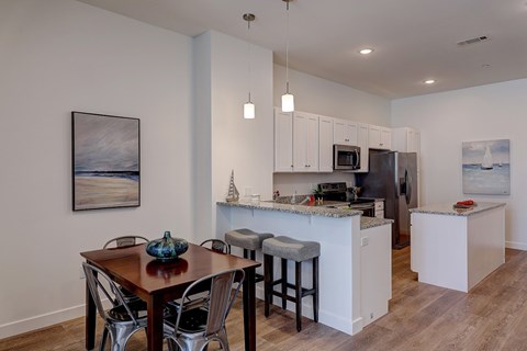 A kitchen with a table and chairs in front of it.