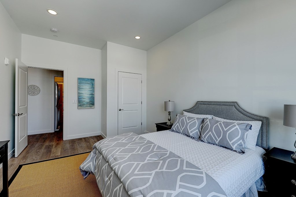 A bedroom with a large bed and a lamp.