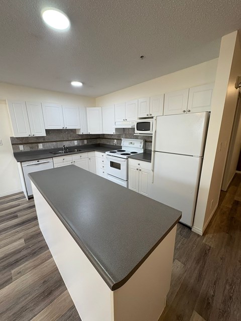 A kitchen with white cabinets and a black countertop.