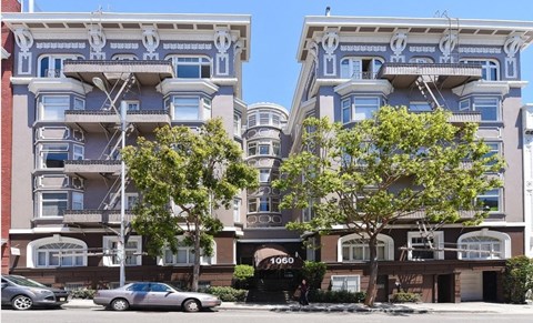 A car is parked in front of a building with the number 1060 on it.