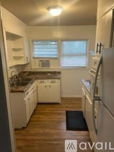 A kitchen with white appliances and wooden floors.