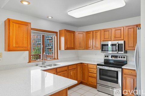A kitchen with white countertops and wooden cabinets.