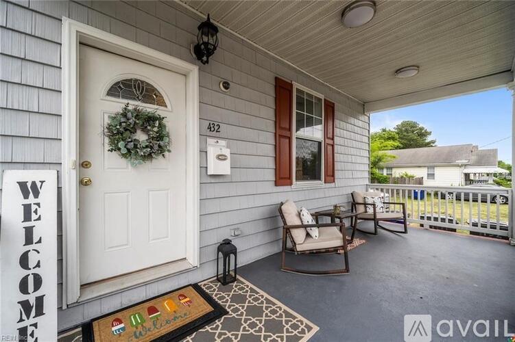 A porch with a welcome mat and two chairs.