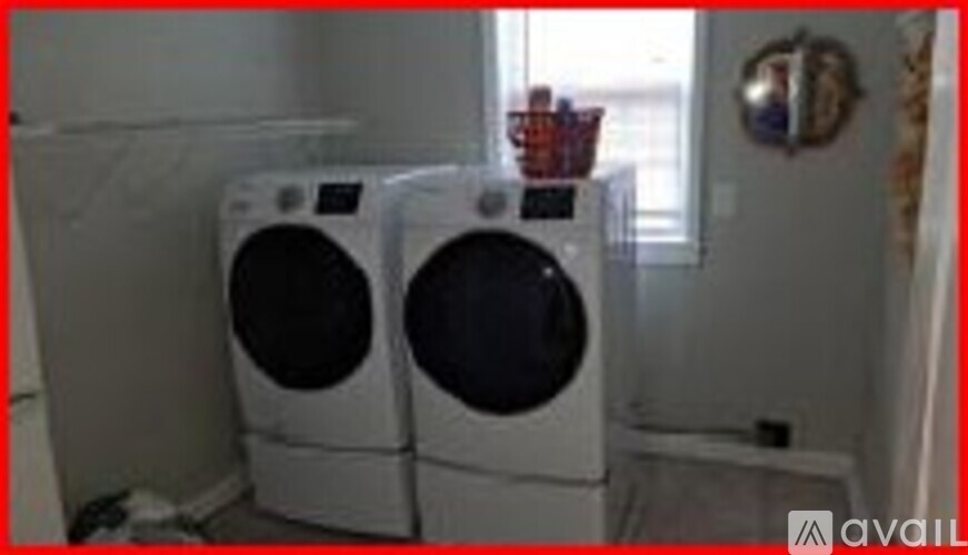A pair of white front loading washing machines in a laundry room.