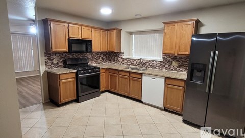 A kitchen with wooden cabinets and a black refrigerator.