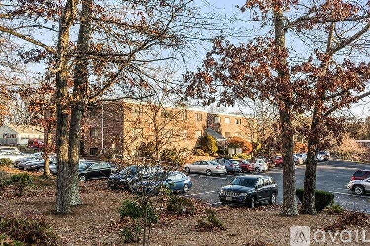 A parking lot with cars and trees in front of a building.