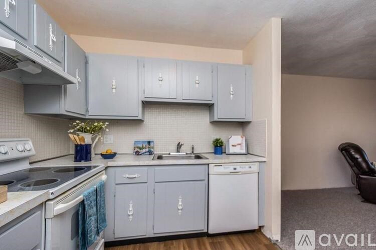 A kitchen with a white stove top oven and a white dishwasher.