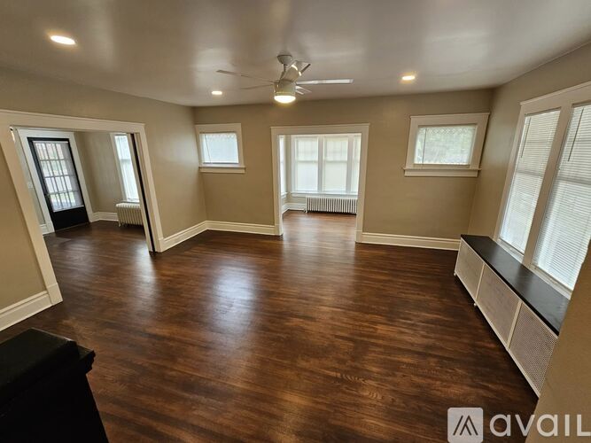 A spacious room with wood flooring and a ceiling fan.