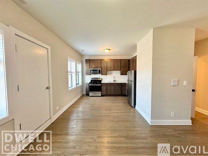 A spacious kitchen with wooden floors and white walls.