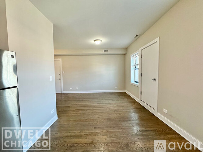 A spacious room with wooden flooring and white walls.