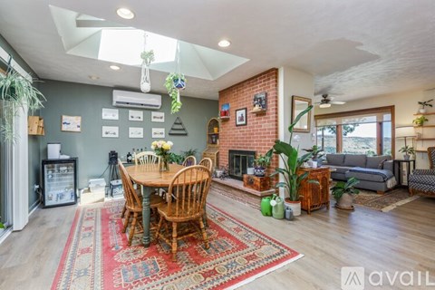 A living room with a dining table and chairs, a couch, and a fireplace.