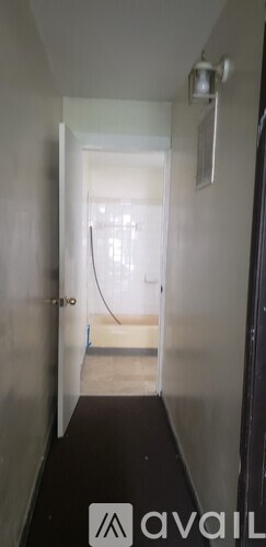 A hallway with a black carpet and white walls.