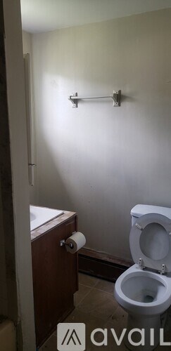 A white toilet in a small bathroom with a towel rack on the wall.