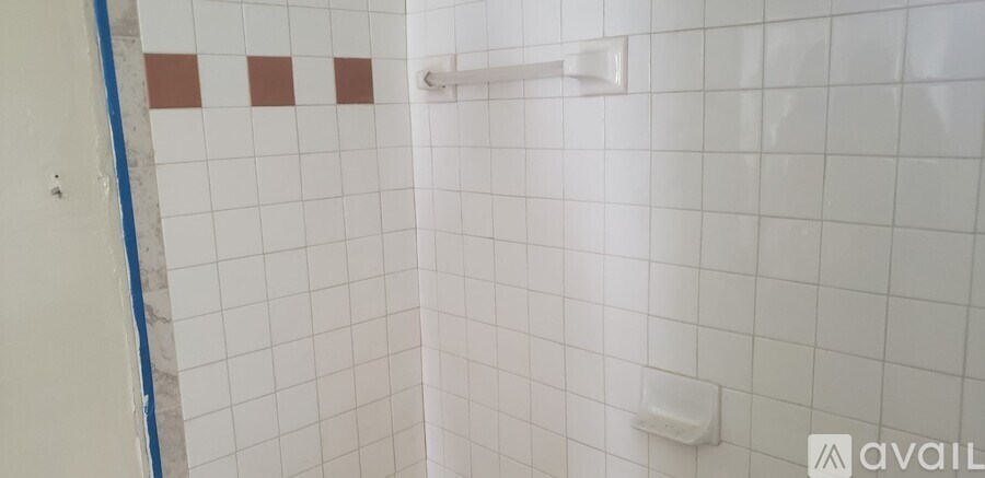 A white tiled shower with a blue line on the wall.