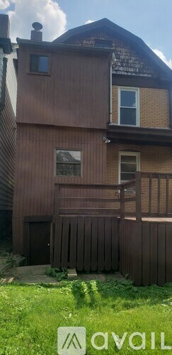 A brown house with a white window and a brown fence.