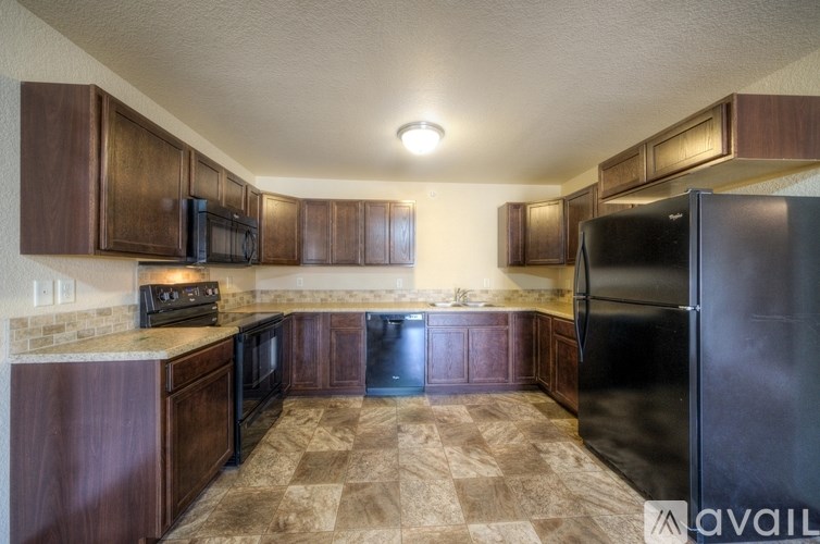 A kitchen with brown cabinets and a black refrigerator.