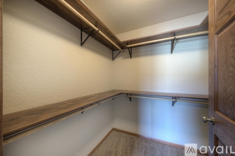 A room with a white wall and a brown shelf.