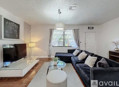 A living room with a black couch and a television.