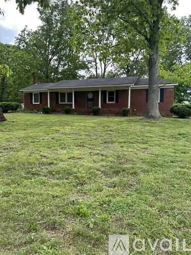 A red brick house with a tree in front.