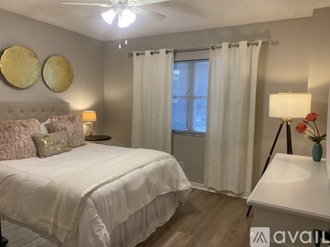 A bedroom with a large bed and a window with curtains.