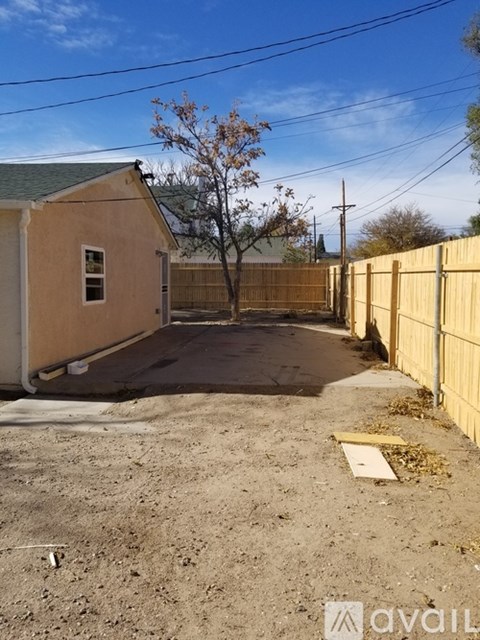 A small house with a white door and a window is available for rent.