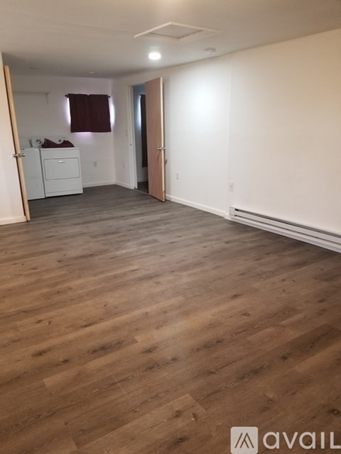 A room with wooden flooring and white walls.