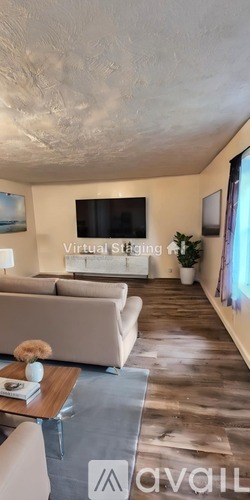 A living room with a couch, a coffee table, and a flat screen TV mounted on the wall.