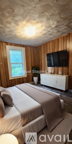 A bedroom with wooden walls and a bed with a white comforter.