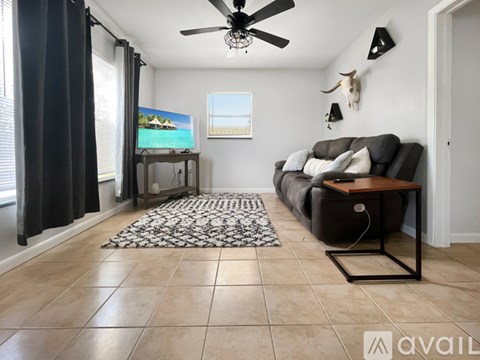A living room with a black couch and a ceiling fan.
