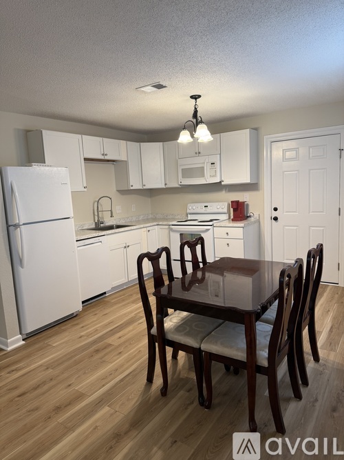 A kitchen with a table and chairs in front of it.