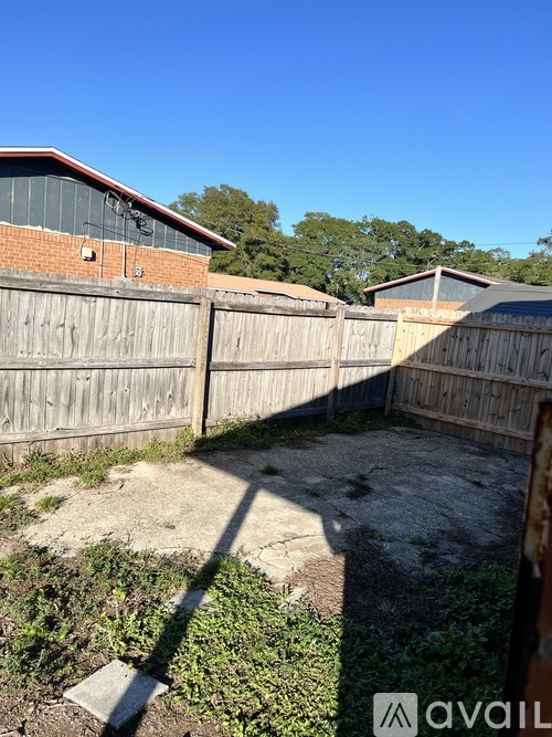 A backyard with a wooden fence and a building in the background.