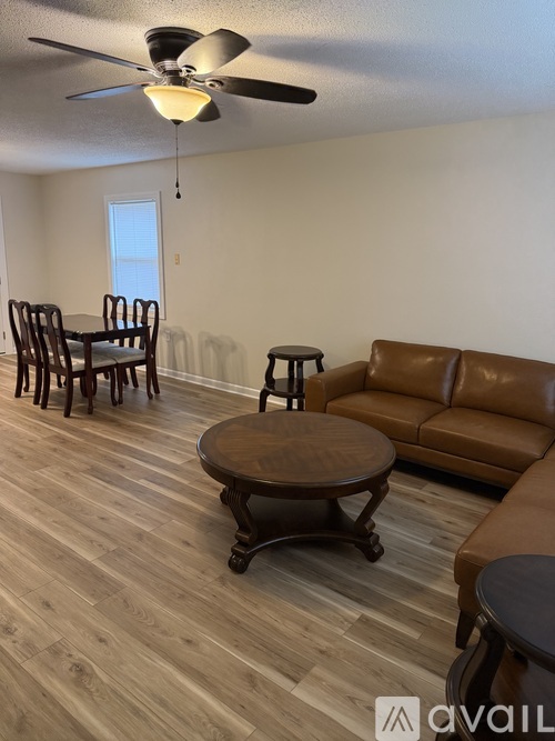 A living room with a brown leather couch, wooden coffee table, and a ceiling fan.