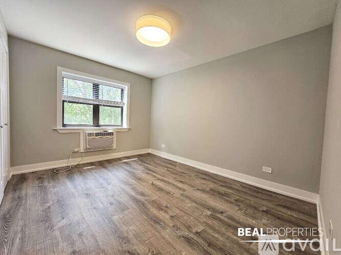 A room with a window and a wooden floor.