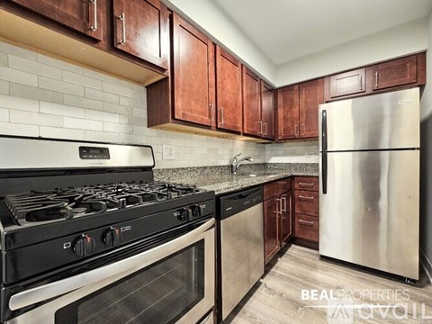 A kitchen with a black stove top oven and a stainless steel refrigerator.