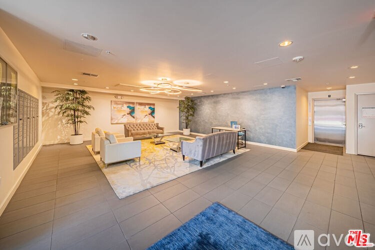 A spacious living room with a white sofa set and a blue rug.