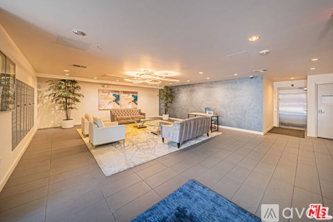 A spacious living room with a white sofa set and a blue rug.