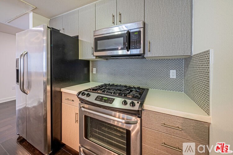 A kitchen with a stainless steel refrigerator, oven, and microwave.