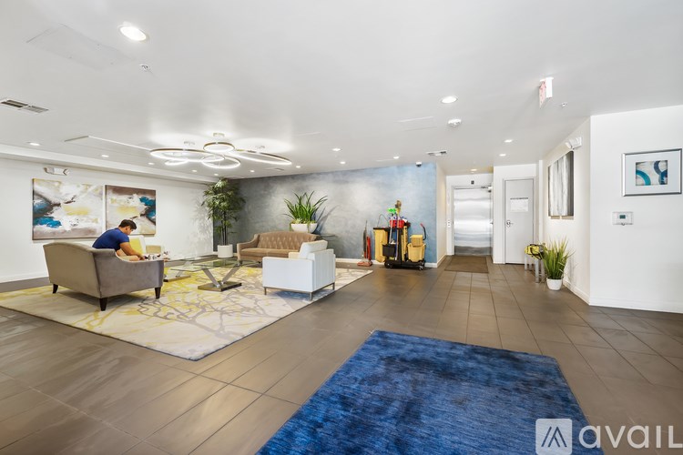 A man is sitting on a couch in a spacious living room.