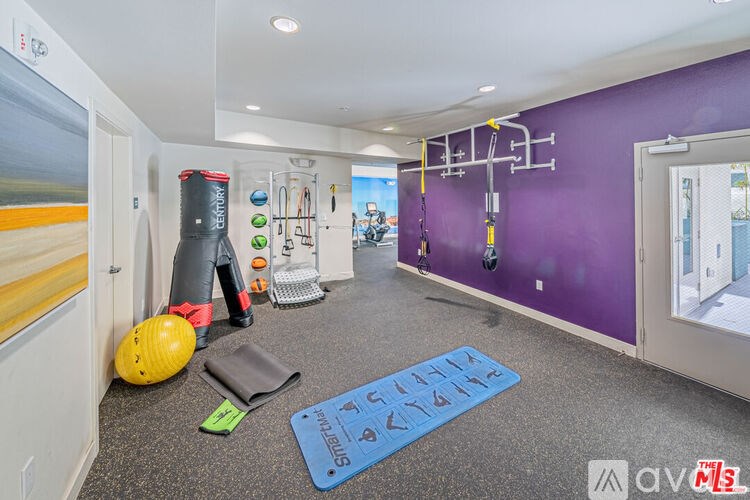 A gym room with purple walls and a variety of exercise equipment.