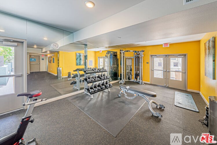 A gym with a variety of equipment including weights and a bench.