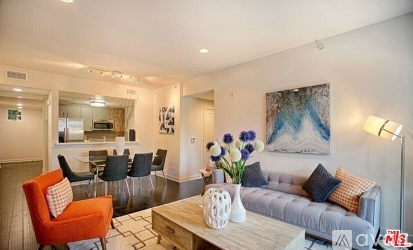 A living room with a grey couch, a red chair, and a painting on the wall.