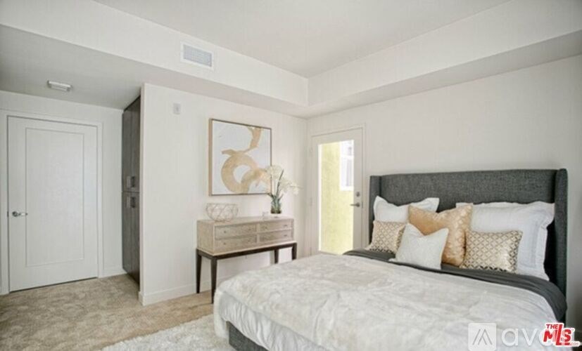 A bedroom with a large bed and a painting on the wall.