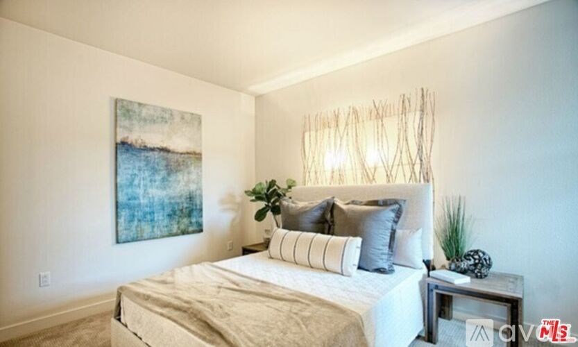 A bedroom with a large bed and a painting on the wall.