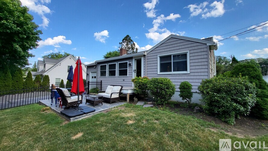 A house with a patio and a red umbrella is for sale.