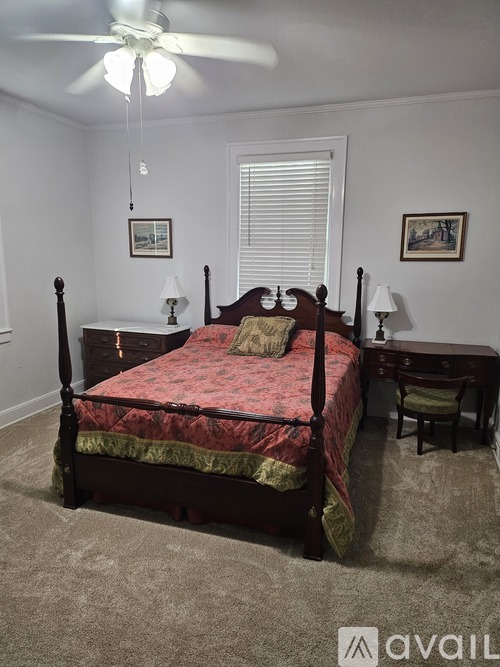 A bedroom with a four poster bed and a ceiling fan.