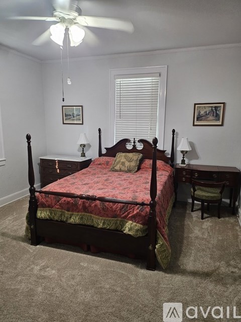 A bedroom with a four poster bed and a ceiling fan.